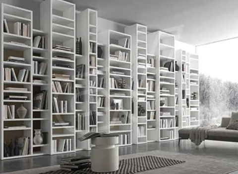 Librería blanca de doble altura junto a una zona de estar