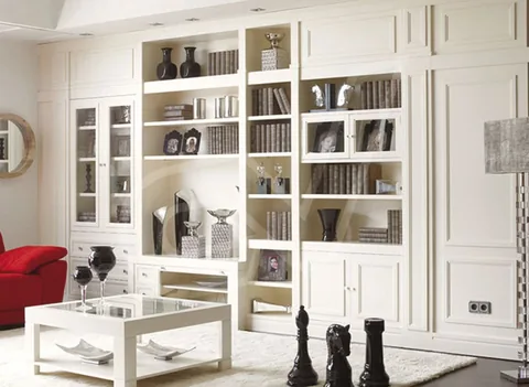 Librería blanca de suelo a techo que enmarca una puerta de paso